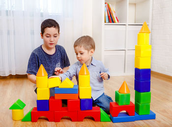 Charming children playing with constructor on floor at home