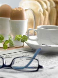 Close-up of coffee cup with newspaper on table