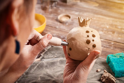 Close-up of a woman potter sculpts a brown clay candlestick in the form of a pomegranate 