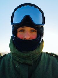 Portrait of man wearing ski goggles against sky during winter