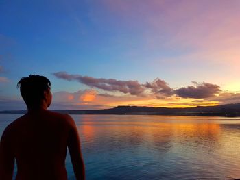 Man looking at sea against sky during sunset