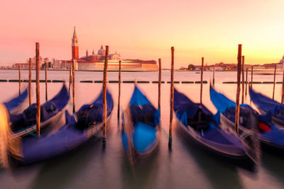 Boats moored in canal at sunset