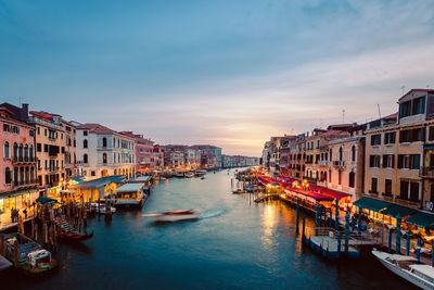 View of venice's grand canal at sunset with illuminated venues on the shores and boats crossing it