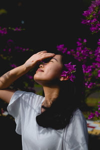 Woman shielding eyes against blooming purple flowers