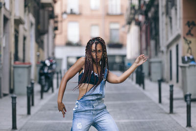 Portrait of woman dancing on street against building