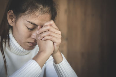 Close-up of young woman praying at church