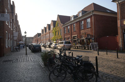 Cars parked on road amidst buildings in city against sky