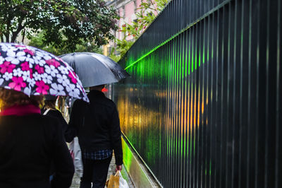 Rear view of people walking on wet glass during rainy season