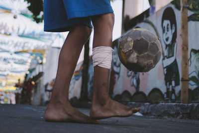 Low section of boy playing soccer on street