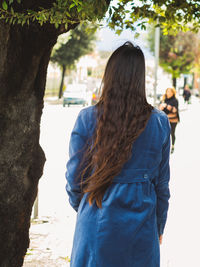 Rear view of woman by tree trunk