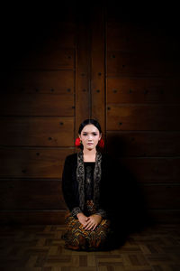 Portrait of woman sitting on wooden floor