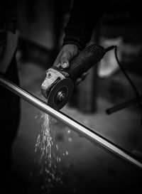 Close-up of hand cutting metal with saw in factory