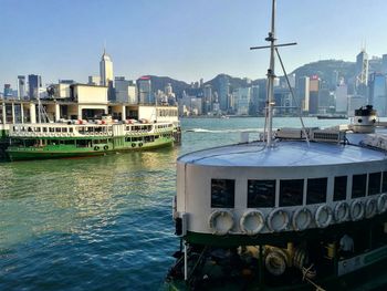 Boats moored in sea against buildings in city