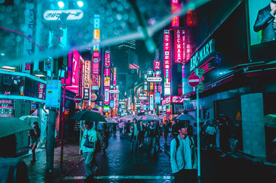 People walking on illuminated street at night