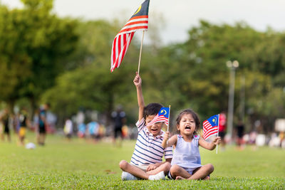 Cute kids playing with flags against trees