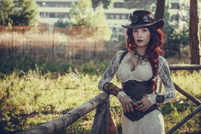 Portrait of young woman with redhead standing by railing in park