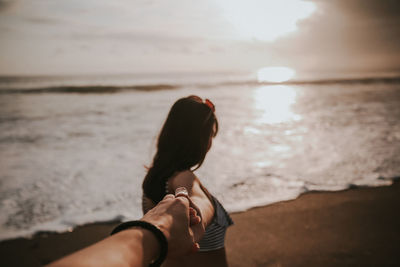 Rear view of woman on beach against sky