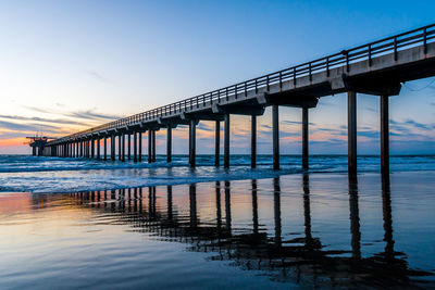 Bridge over sea against sky during sunset