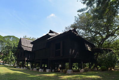 Built structure on field by houses against sky