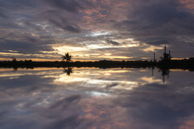 Scenic view of lake against dramatic sky during sunset