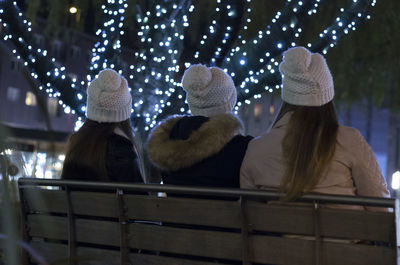 Rear view of women sitting against illuminated lights