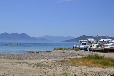 Boats in calm sea against clear sky