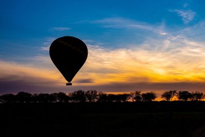 Silhouette hot air balloon against sky during sunset