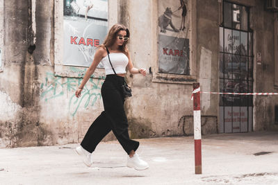 Side view of young woman against graffiti wall in city