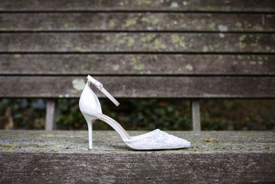 Close-up of white shoes on bench against wall