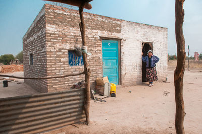 Rear view of man standing by building against sky
