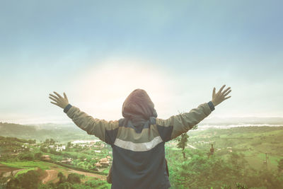 Rear view of man standing on landscape against sky