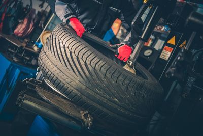 Midsection of mechanic repairing tire in workshop