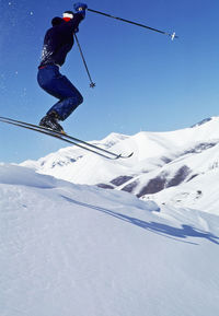 Man skiing on snowcapped mountain against sky