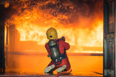 Rear view of firefighter spraying water on fire