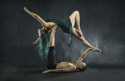 Full length of couple performing modern dance against gray background