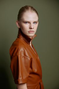 Portrait of young woman standing against wall