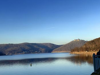 Scenic view of lake and mountains against clear blue sky