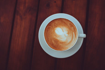 Two cups of cappuccino with latte art on the wooden table. beautiful foam and ceramic cup