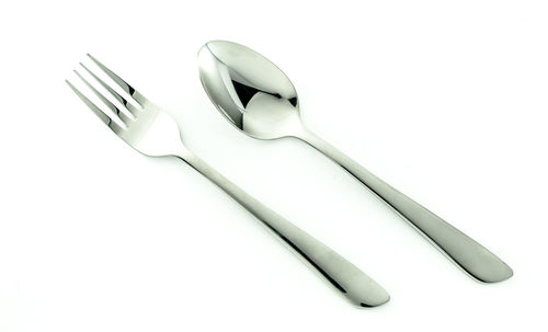 Close-up of fork and spoon over white background