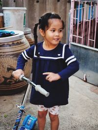 Side view of girl looking away while standing by push scooter