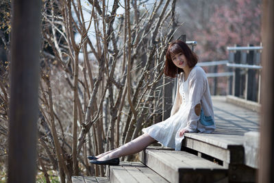 Portrait of young woman sitting on tree trunk