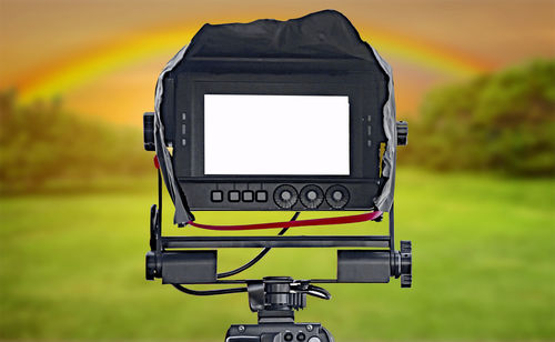 Close-up of digital camera against sky