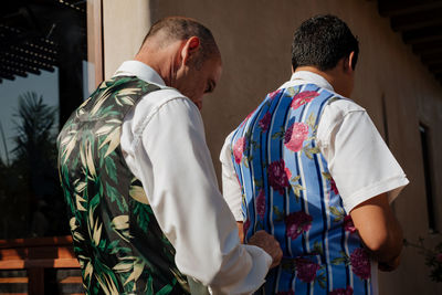 Rear view of friends standing against building