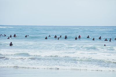 People at beach against clear sky