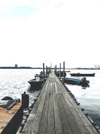 Pier over calm sea against clear sky