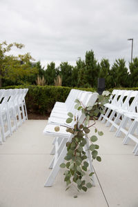 Chairs and table by trees against sky