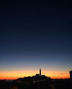 Silhouette cityscape against clear sky at sunset