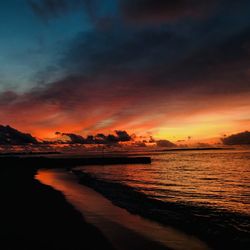 Scenic view of sea against dramatic sky during sunset