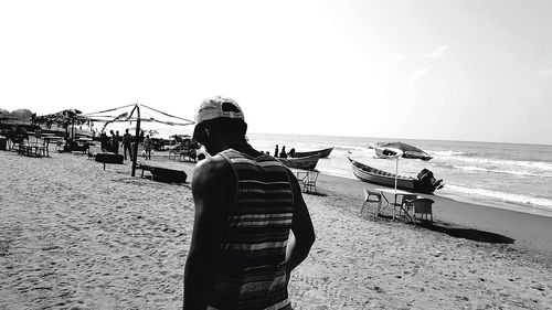 Rear view of people on beach against clear sky