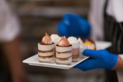 Midsection of person holding ice cream on table